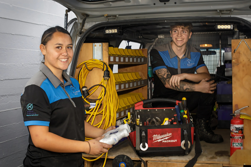 Two apprentices getting plumbing fixtures from the back of a van
